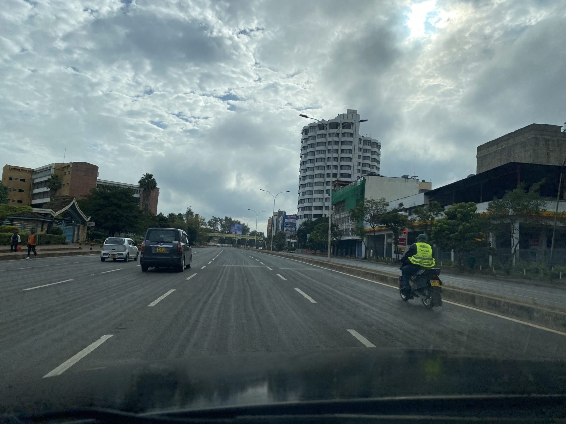 A vibrant cityscape with a mix of modern skyscrapers and traditional African architecture, surrounded by lush greenery and wildlife. The iconic Mount Kenya looms in the distance, while locals go about their daily activities in the bustling streets